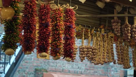 Close-up-slow-motion-shot-of-a-bunch-of-spices,-peppers,-and-garlic-hanging-from-the-ceiling-in-the-street-market-of-Pike-Place-in-Seattle-Washington