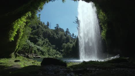 Inside-cave-view-behind-powerful-Omanawa-waterfall-in-New-Zealand-on-sunny-day