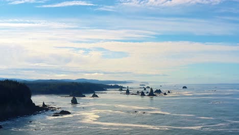 Stunning-aerial-drone-time-lapse-of-the-gorgeous-Third-Beach-in-Forks,-Washington-with-large-rock-formations,-cliffs,-small-waves-and-sea-foam-on-a-warm-sunny-summer-morning