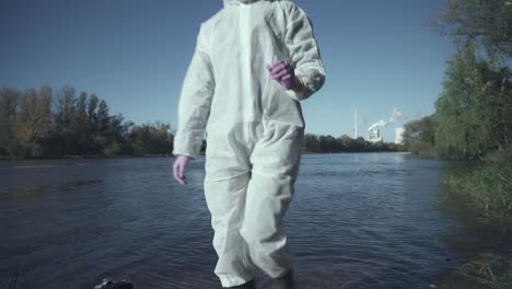 Suitcase-with-test-tubes-and-person-in-protective-suit-checking-river-sample,-outside-view,-industrial-background