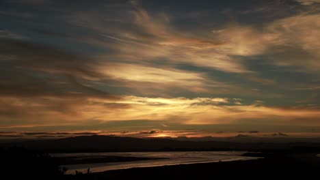 Atemberaubender-Friedlicher-Goldener-Sonnenuntergang-In-Whakatane-Mit-Beleuchteten-Wolken,-Schwenk-Nach-Unten