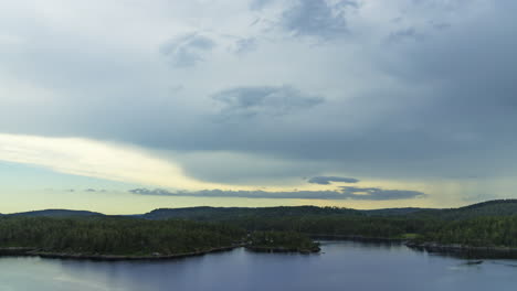 Time-lapse-of-dark-clouds-moving-over-forest-and-sea,-summer-evening-in-South-Norway
