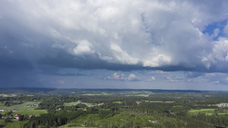 Aerial-Hyperlapse-of-dark-clouds-moving-over-forest-and-countryside-of-South-Norway---tracking,-drone-shot