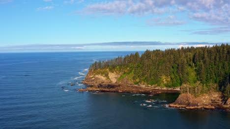 Stunning-aerial-drone-dolly-out-shot-of-the-gorgeous-Third-Beach-in-Forks,-Washington-with-a-forest-or-large-green-pine-trees-on-cliffs-on-a-warm-sunny-summer-morning-with-clouds