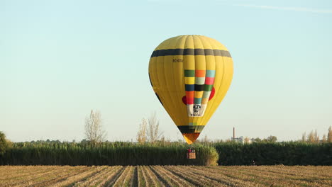 Yellow-Hot-Air-Balloon-Flying-Over-Rural-Fields-In-Coruche,-Ribatejo,-Portugal
