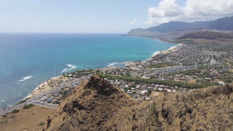 Cliffside-mountain-ridge-on-tropical-beach-with-blue-ocean-and-city