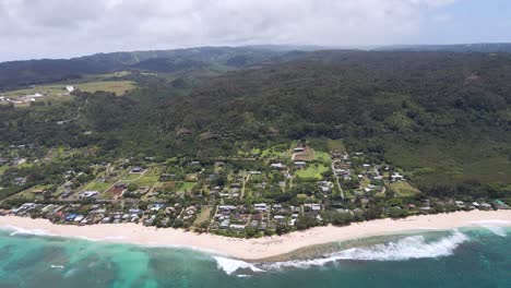 Aerial-view-of-tropical-island-and-water-coastline-on-the-beach-and-mountains-covered-in-forests-in-the-background