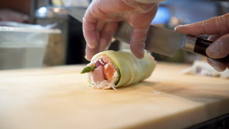 Chef-Cortando-Maki-De-Sushi,-Chef-De-Sushi-Rebanando-Rollo-De-Sushi-Envuelto-En-Pepino-Con-Cuchillo,-Cámara-Lenta-Hd