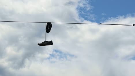 Close-up-of-a-pair-of-shoes-tied-together-dangling-from-a-power-line-in-Seattle,-Washington-on-a-warm-sunny-summer-day