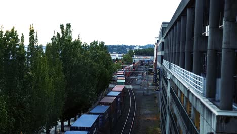 Tilting-up-shot-of-an-old-cargo-train-moving-down-the-track-in-Seattle,-Washington-during-dusk-on-a-cloudy-overcast-day
