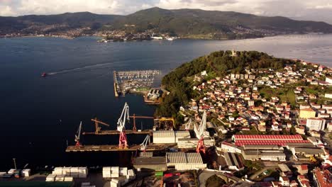 Luftaufnahme-über-Das-Sonnige-Küstengebirge-Von-Vigo,-Spanien,-Beherbergt-Industriekräne-Und-Kleine-Dörfliche-Meereslandschaften