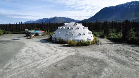 Igloo-Shaped-building-in-Alaska-on-Dirt-lot-surrounded-by-mountains
