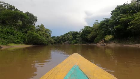 Traveling-on-a-wooden-boat-through-a-murky-river-in-the-forest--Wide