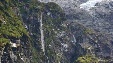 Extreme-waterfall-crashing-down-the-rocky-mountains-of-New-Zealand-with-snow-on-the-peak---Rob-Roy-Glacier,New-Zealand