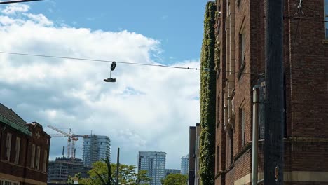 A-pair-of-shoes-tied-together-dangling-from-a-power-line-in-Seattle,-Washington-on-a-warm-sunny-summer-day