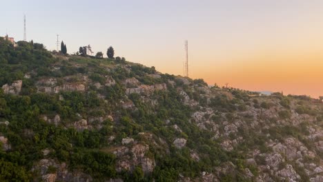 Electricity-Pylons-And-Communication-Towers-On-Rocky-Mountain-In-Kaslik,-Keserwan-District,-Lebanon-With-Golden-Hour-Sunset-By-The-Sea-Revealed