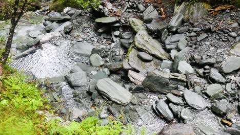 Top-Down-Aufnahme-Eines-Ruhigen-Fließenden-Flusses-Zwischen-Felsen-Und-Steinen-In-Der-Natur-An-Sonnigen-Tagen,-Nahaufnahme
