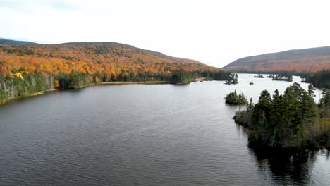 Flying-over-New-England-Lake-in-Mountains-during-fall-changing-leaves