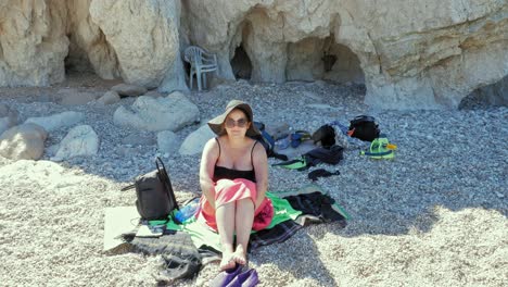 Tourist-Woman-Sitting-On-The-Pebble-Beach-Of-Agia-Eleni-In-Greece---wide,-static