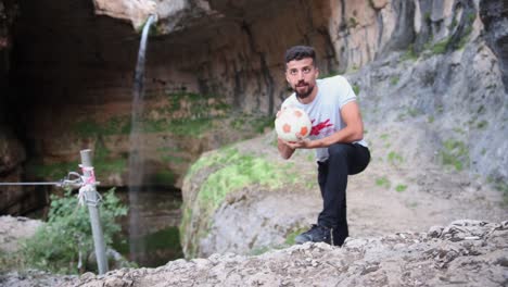 Man-With-Soccer-Ball-Blogging-In-Front-Of-Baatara-Gorge-Waterfall-In-Tannourine,-Batroun,-Lebanon
