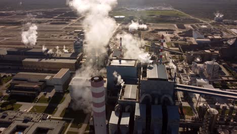 Massive-amount-of-steam-ejected-into-air-in-huge-factory-facilities,-aerial-drone-view