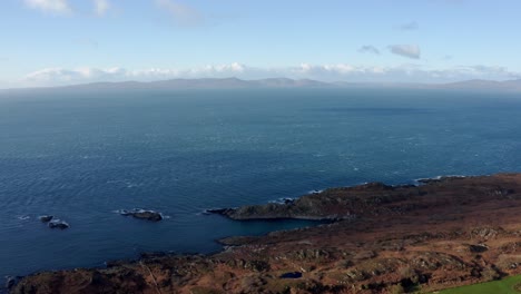 AERIAL---Hills-on-the-horizon,-blue-sky-over-the-Isle-of-Gigha,-Kintyre,-Scotland