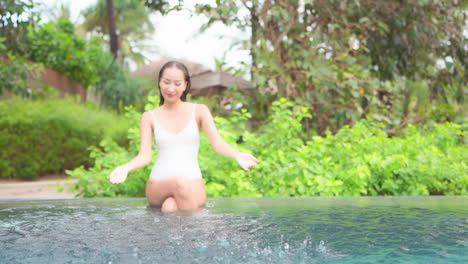 A-playful-young-woman-splashes-water-from-the-swimming-pool-into-the-air