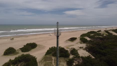 Antenna-on-deserted-beach-with-ocean-in-background,-Mar-de-las-Pampas-in-Argentina