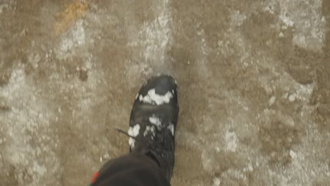 POV-Of-Man-Wearing-Black-Boots-Walking-On-Frozen-Ground-In-Winter