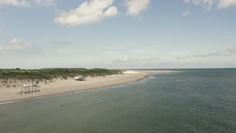 Aerial-shot-moving-past-a-beautiful-white-beach-at-high-tide-on-a-sunny-day