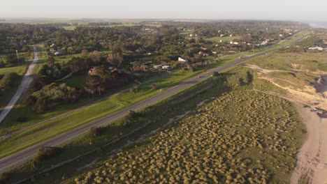 Aerial-drone-shot-of-rural-road-with-driving-cars-during-sunset-time-in-Mar-del-Plata,Argentina