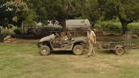 Farmer-loading-an-utv-all-terrain-vehicle-in-a-farm-with-seeds-and-plants,-transport