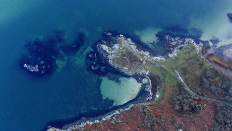 AERIAL---Turquoise-waters,-Isle-of-Gigha,-Kintyre,-Scotland,-rising-top-down-view