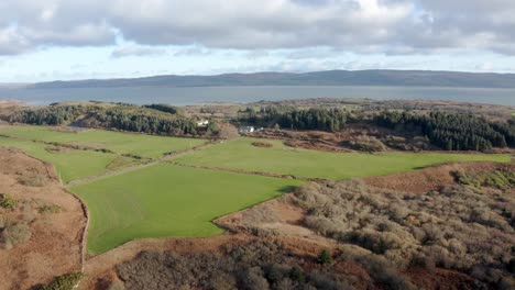 AERIAL---Green-pastures-and-farmland,-Isle-of-Gigha,-Kintyre,-Scotland,-rising