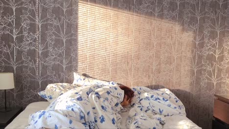 Time-lapse-of-person-sleeping-in-bed-with-morning-sunrays-moving-on-bedroom-wall