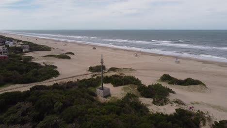 Circling-close-up-shot-of-the-green-antenna-in-front-to-the-ocean-which-is-close-to-the-town-beach-at-Mar-de-las-Pampas,-Argentina