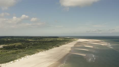 Aerial-shot-flying-high-over-a-beautiful-white-beach-and-green-dunes-in-Oranjezon-nature-reserve-in-Zeeland,-the-Netherlands