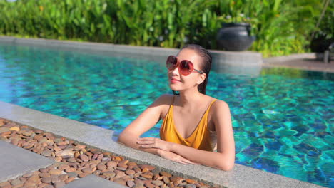An-attractive-woman-fresh-from-swimming-leans-along-the-edge-of-a-swimming-pool