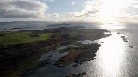 AERIAL---Wind-power-turbines-at-sunrise,-Isle-of-Gigha,-Kintyre,-Scotland,-reverse
