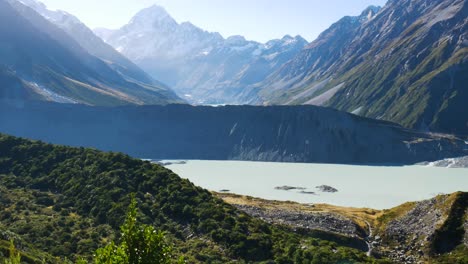 Panning-shot-of-picturesque-mountains-range-with-Tasman-Mueller-Lake-during-sunny-day-in-New-Zealand