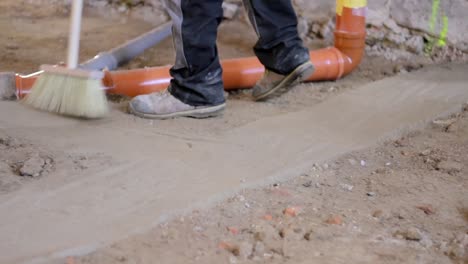 Arbeiter,-Der-Einen-Staubigen-Boden-Mit-Abwasserrohren-Auf-Der-Bodenfläche-Fegt-Stockvideo