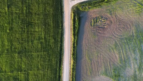 An-aerial-of-a-small-gravel-road-path-on-a-green-field-during-summer-in-Estonia