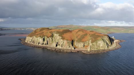 AERIAL---Epic-shot-of-sunbathed-Island-Davaar,-Kintyre,-Scotland,-reverse-rising