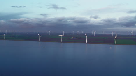 Dramatic-sky-above-the-flat,-dutch-landscape,-covered-in-wind-turbines-on-the-lakeshore