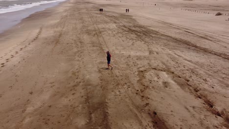 Old-man-walking-alone-on-beach-at-Mar-de-las-Pampas,-Argentina