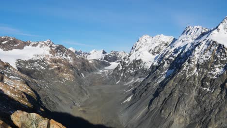 Impresionante-Panorama-Aéreo-De-Enormes-Montañas-Cubiertas-De-Nieve-Contra-El-Cielo-Azul-Y-La-Luz-Del-Sol---Caminata-Por-La-Cabaña-De-Mueller,-Nueva-Zelanda