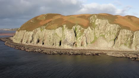 AERIAL---Dramatic-shot-of-sunbathed-Island-Davaar,-Kintyre,-Scotland,-reverse-rising