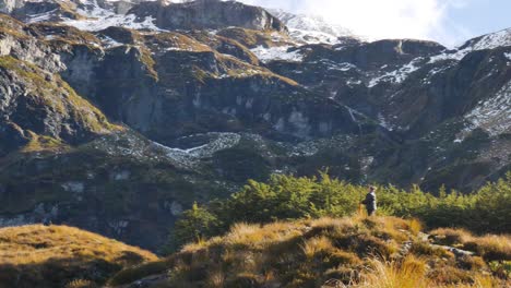 Female-Hiker-hiking-in-front-of-beautiful-mountain-panorama-during-sunny-day---Rees-Valley,Fiordland-National-Park