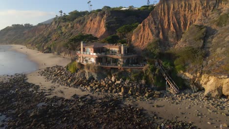 Aerial-view-Super-Luxury-home-facing-the-ocean,-Expensive-real-state-facing-the-ocean-in-El-Matador-beach-state-park-in-Malibu-California-during-golden-hour,-vacation-rentals