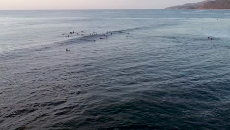 Surfers-at-sunset-waiting-for-the-perfect-wave-to-catch-in-Sayulita,-Mexico